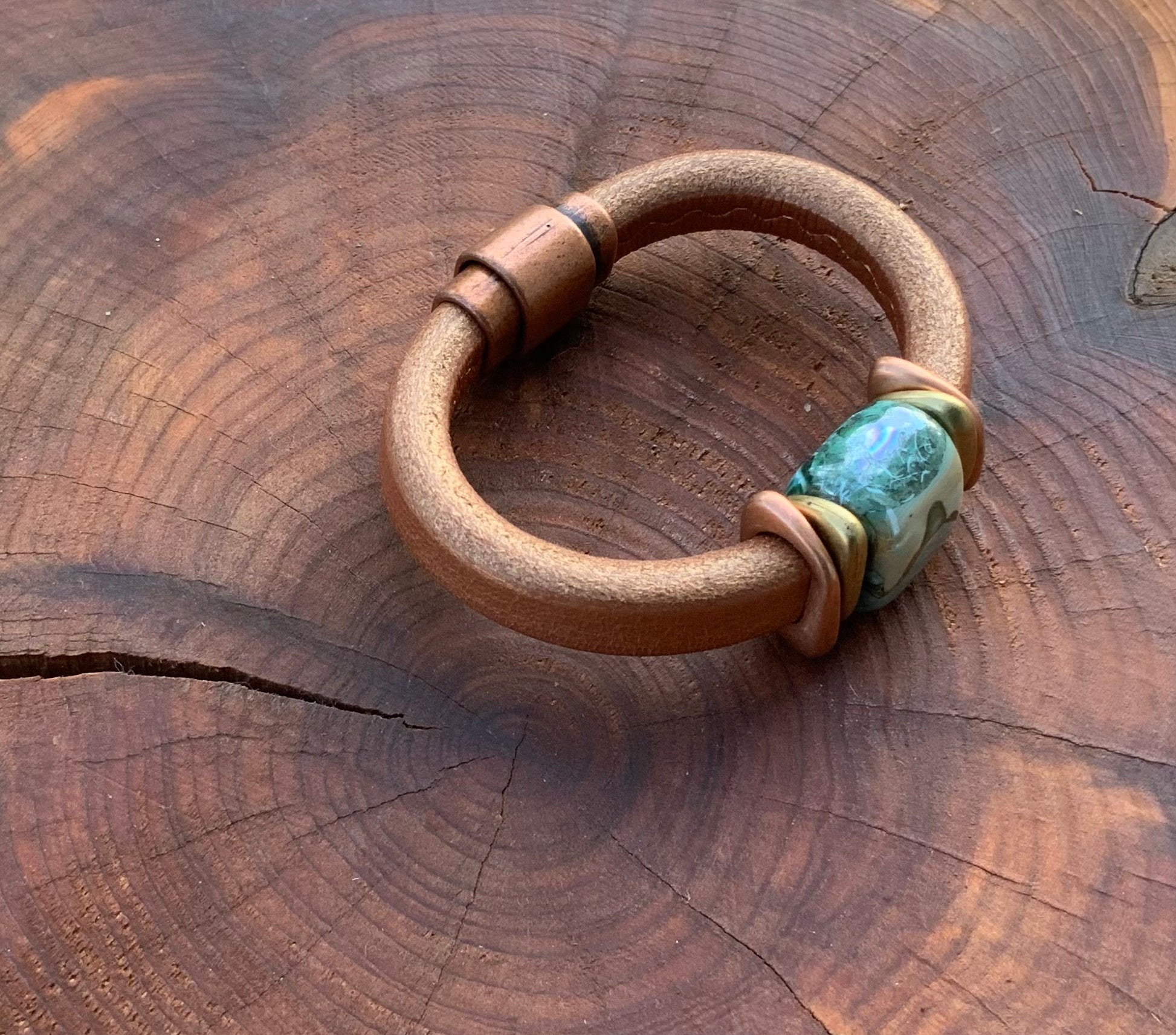 Tuscan Sunset Ceramic Bracelet features a unique ceramic bead with blues and greens on a shimmery copper leather band.