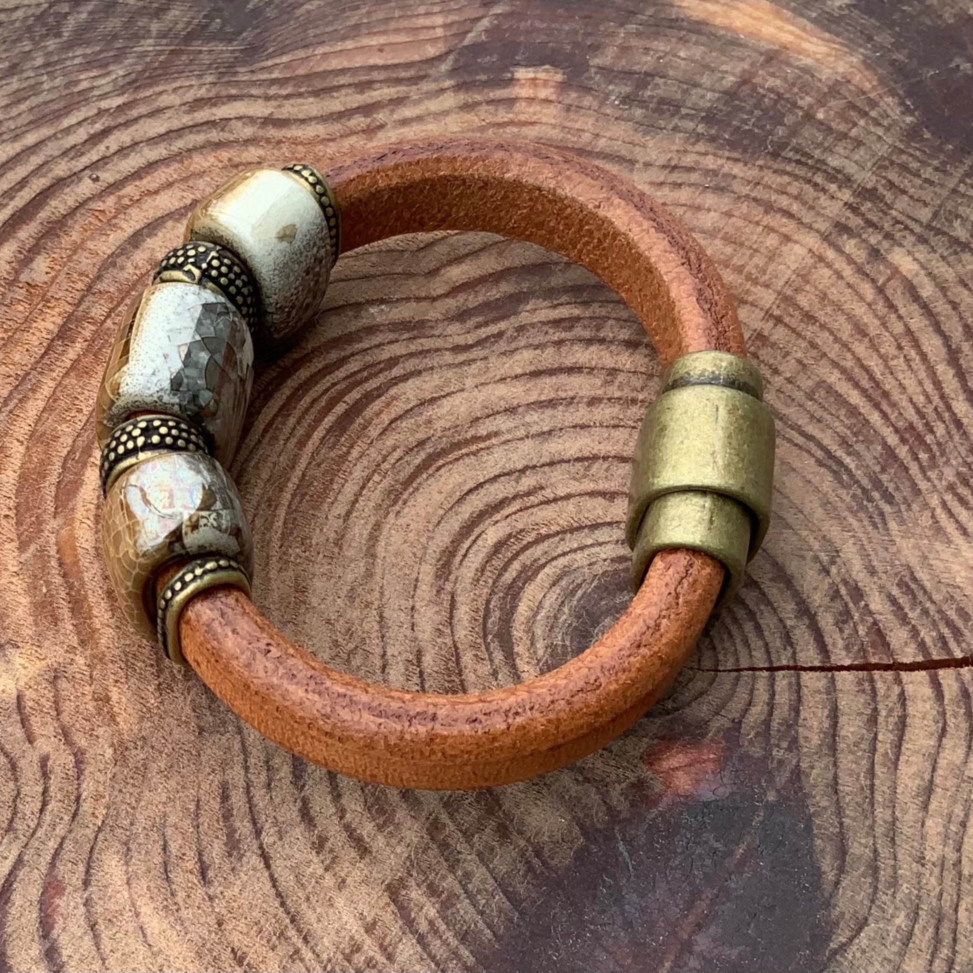 Genuine leather River Rock Ceramic Bracelet featuring unique handmade ceramic beads in tan and gray with brass closure.